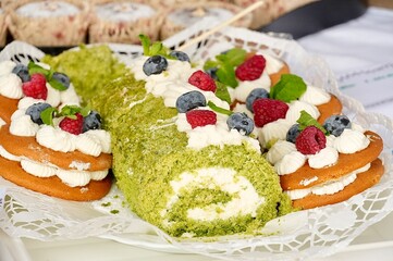 Cake roll with cream and fresh berries on a white plate.