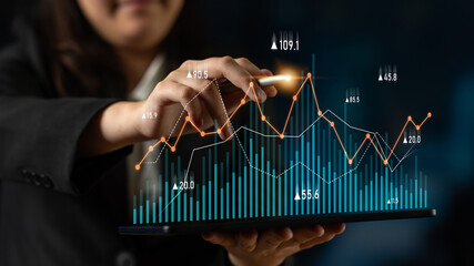 A businesswoman interacts with a digital tablet displaying various data trends and charts in a contemporary office setting, emphasizing data-driven decision-making. Scalp