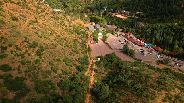Approaching the small railway station and parking lot, highway and some houses at the mountain foot. Infrastructure near the Manitou Springs Incline, Colorado, USA. Top view.