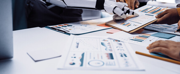 A dynamic scene depicting human collaboration with a robotic arm in a modern office, focused on data analysis and innovative strategy development.Noogenesis