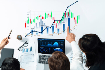 A diverse business team collaborates in a modern office, analyzing financial graphs and data on a...
