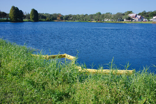Florida lake with Curved Shape Yellow Water Goat. Chain of floating buoys anchored across a body of water near outlet to help control pollution and clean up. Green grass and calm water