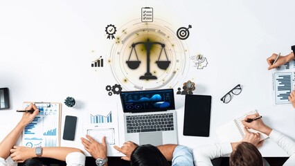 Diverse professionals engage in a collaborative strategy session, using a laptop and notebooks,...