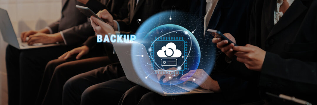 Business professionals engage with technology, focusing on cloud backup solutions. The scene captures modern devices and a digital interface in a dynamic workspace. Trope