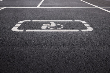 Fototapeta premium car parking space on asphalt, white worn markings, textured pavement, Handicap sign represents accessibility, inclusivity, equal rights, and consideration for individuals with disabilities