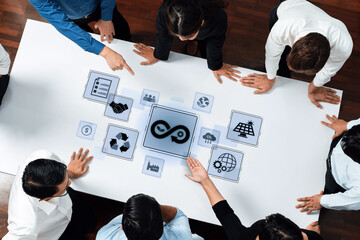 A diverse business team engages in a collaborative meeting, exploring sustainable development concepts with digital icons symbolizing innovation and teamwork. Trope