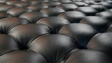 Close-up of black leather sofa texture with soft tufted pattern