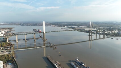 Aerial drone view of Queen Elizabeth bridge and large cargo ships docked on the river Thames in Dartford at sunset, UK