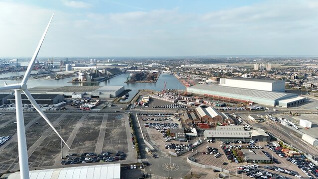 Aerial drone view of Tilbury docks, industrial shipping wharf and port, warehouses and wind turbines near London UK
