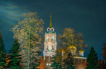 The majestic bell tower of the Assumption Cathedral behind the Tula Kremlin wall, brightly illuminated at night. A fairytale view of Russian Orthodox architecture in Tula, Russia.