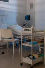 A clean and organized hospital room that features a bed along with necessary medical equipment