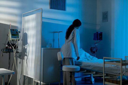 Night shift caregiving, Healthcare professional organizing restful patient space, Dedicated nurse meticulously arranges soothing patient area with all necessary medical