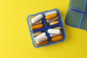 Medications are meticulously organized in a pill organizer placed on a vibrant background