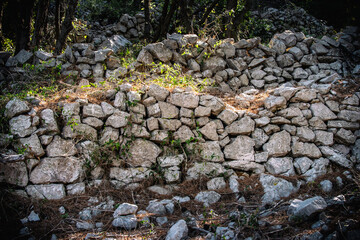 Old, stone drywall in the overgrown bush at the village of Valun, on the Cres island, Croatia