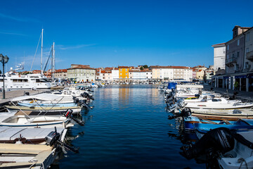 Cres town city port with anchored boats and vessels with old, colorful houses in the background