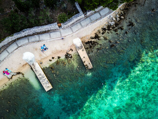 Top down aerial view of beautiful, secluded beach in the small bay of Cres island, Croatia, with beatiful, turquoise sea splashing the sand shore