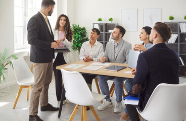 Gathering for meeting in modern office, diverse group of colleagues sitting listening, talking or presenting, participant discussing ideas, collaborating, interaction on business discussion, teamwork 