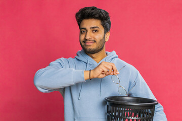 Indian young man taking off throwing out glasses into bin after medical vision laser treatment...