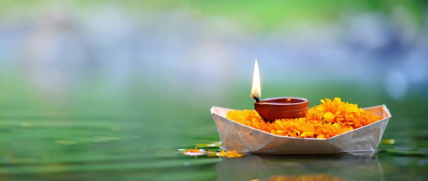 Leaf boat with diya and marigold flowers floating on water, wide banner format with copy space, Kartik Purnima ritual, peaceful spiritual offering, traditional Hindu ceremony scene