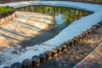 Maintenance and cleaning of a large pond in a garden or public park. Mud on the bottom of the artificial pond, drained water, and waterproofing coating