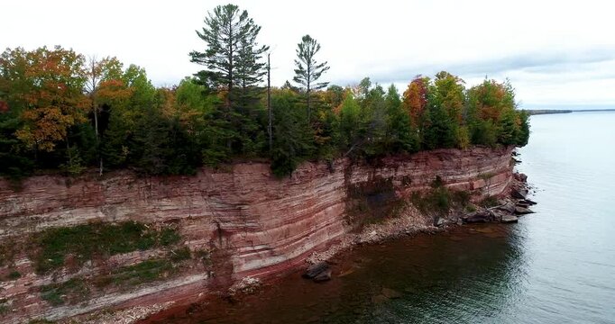 Aerial 4K drone footage flying left to right along sandstone cliffs and fall foliage at Baraga Cliff Roadside Park overlooking Keweenaw Bay, Michigan