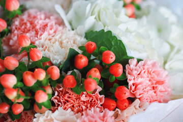 Macro shot of vibrant red hypericum berries with peach and pink carnations and white hydrangeas in a romantic floral bouquet
