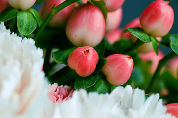Macro shot of vibrant red hypericum berries with peach and pink carnations and white hydrangeas in a romantic floral bouquet
