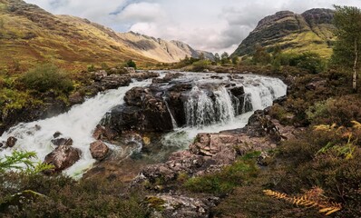 A panoramic view of a waterfall, during an early morning autumn hike in Scotland highlands, along the River Coe in Glencoe, UK