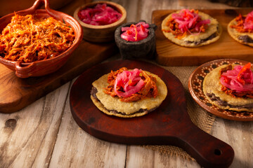 Panuchos, a typical dish from Yucatan, Mexico. A handmade, fried corn tortilla filled with beans, topped with cochinita pibil, pickled red onion, and habanero pepper.