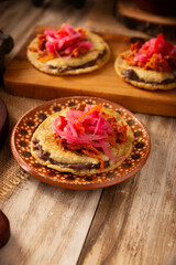 Panuchos, a typical dish from Yucatan, Mexico. A handmade, fried corn tortilla filled with beans, topped with cochinita pibil, pickled red onion, and habanero pepper.