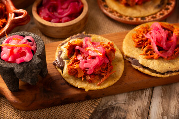 Panuchos, a typical dish from Yucatan, Mexico. A handmade, fried corn tortilla filled with beans, topped with cochinita pibil, pickled red onion, and habanero pepper.