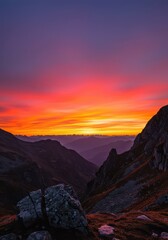 Fototapeta premium Vibrant orange and pink sunset over jagged mountain peaks and vast rugged landscape, quiet evening light illuminates the wilderness scene ,alpine ,mountains ,remote