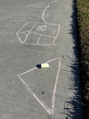 Children's Chalk Art: Colorful and naive chalk drawings created by kids on a grey concrete sidewalk, showing creativity.