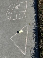 Children's Chalk Art: Colorful and naive chalk drawings created by kids on a grey concrete sidewalk, showing creativity.