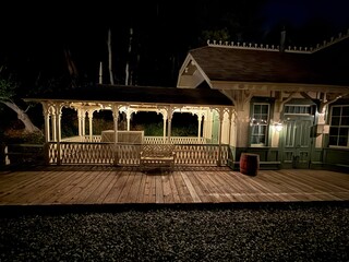 Vintage Train Station at Night: A nostalgic depot with a wooden walkway, illuminated by warm lights under a dark sky, evoking history.