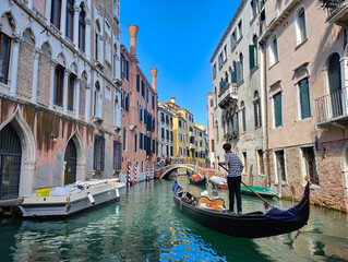 Scenic view of a canal with gondola and old venetian architecture on a sunny day. Venice, Italy