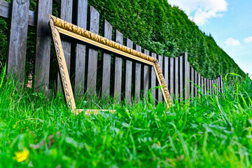 Ornamental gold frame propped against a tidy wooden fence