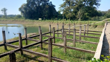 Old unfinished concrete bridge frame near riverbank under bright daylight.