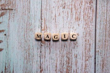 Letter cubes forming the word “Magic” on a bright peeling wooden background, symbol of magic and imagination