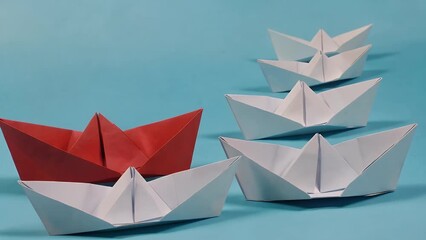 collection of miniature vessels constructed from white paper all oriented in a single direction  contrasted with a solitary red paper vessel pointing an alternate way  set against an azure colored