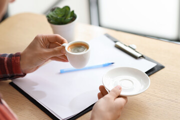 Woman having coffee break at wooden desk indoors, closeup