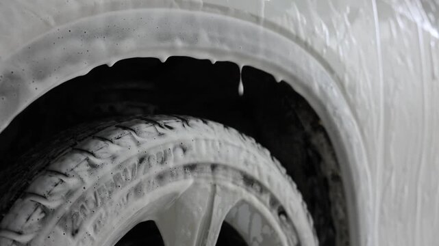 Auto covered with cleaning foam at car wash, closeup