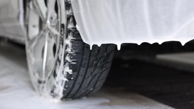 Auto covered with cleaning foam at car wash, closeup