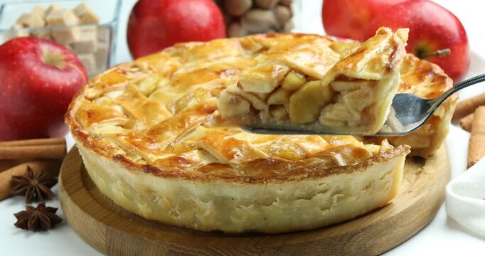 Taking delicious homemade apple pie with spatula at white wooden table, closeup