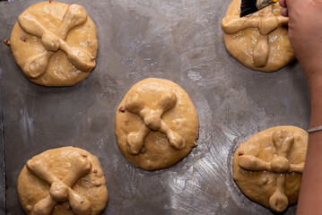Hand brushing pan de muerto with glaze for dia de muertos