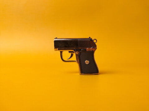 A small handgun is on a yellow background