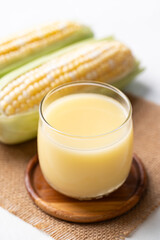 Sweetcorn milk in glass and fresh sweetcorn on white background, Alternative milk from plant, dairy free