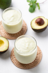 Avocado smoothie with milk in glass and avocado fruit on white background, Healthy drink