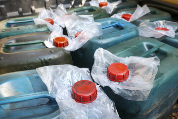 Close up view of many old blue plastic jerrycans with red caps for storing liquid. collection of...
