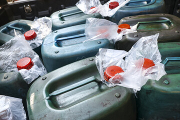 Close up view of multiple green plastic jerrycans with red caps for fuel storage. grim scene of...